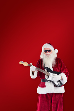 Santa Claus plays guitar with sunglasses against red backgroundの写真素材