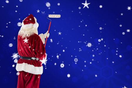 Santa has a globe in his hand against blue snowflake backgroundの写真素材