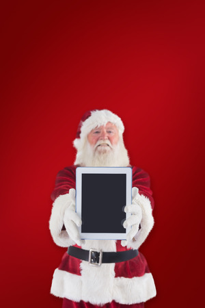 Santa presents a tablet PC against red backgroundの写真素材
