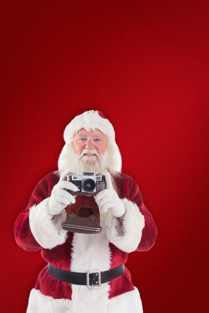 Santa is taking a picture against red backgroundの写真素材