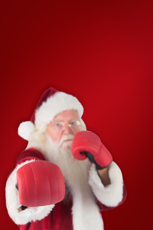 Santa Claus punches with his right against red backgroundの写真素材