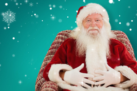 Santa holding his belly on the armchair against greenの写真素材