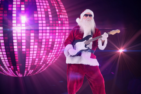 Santa Claus plays guitar with sunglasses against digitally generated cool disco ball designの写真素材