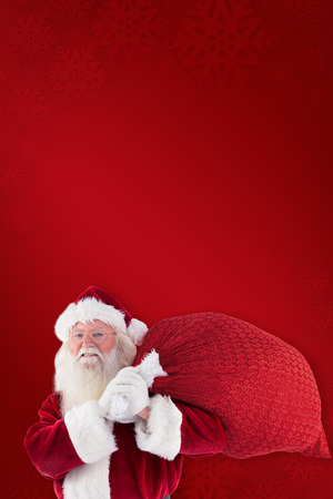 Composite image of santa claus carrying sack against red backgroundの写真素材