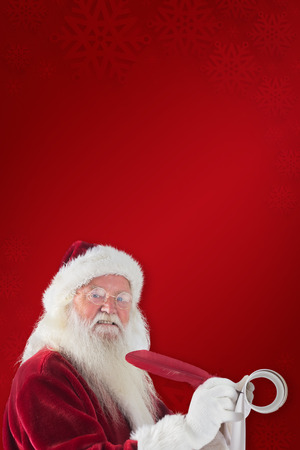 Father Christmas writes a list against red backgroundの写真素材