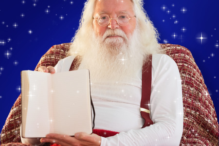 Father christmas showing a book against blueの写真素材