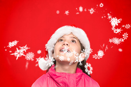 Festive little girl looking surprised against red backgroundの写真素材