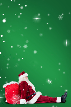 Santa sits leaned on his bag against greenの写真素材