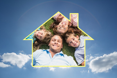 Happy family lying on the grass in a circle against cloudy sky with sunshineの写真素材