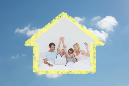 Family using a laptop in bed against cloudy skyの写真素材