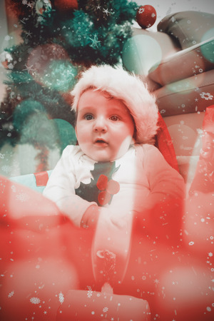 Cute baby boy in large christmas present against candle burning against festive backgroundの写真素材