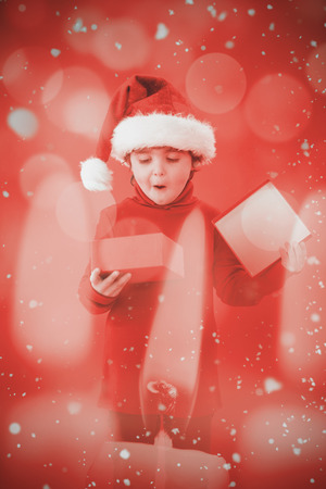Festive little boy opening a gift against candle burning against festive backgroundの写真素材