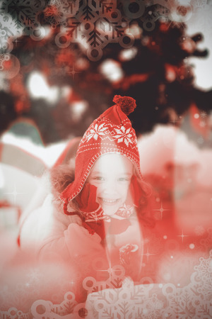 Festive little girl in hat and scarf against candle burning against festive backgroundの写真素材
