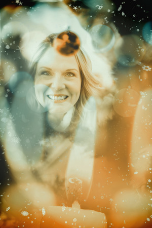 Festive blonde hanging bauble on christmas tree against candle burning against festive backgroundの写真素材