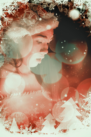 Amazed brunette in santa outfit opening a gift against twinkling red and orange lightsの写真素材