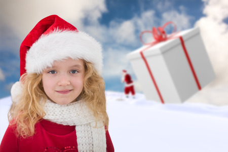 Cute girl in santa hat against blue sky with white cloudsの写真素材