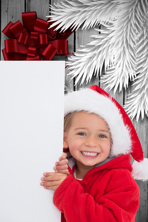 Festive little girl showing poster against wood with festive bowの写真素材