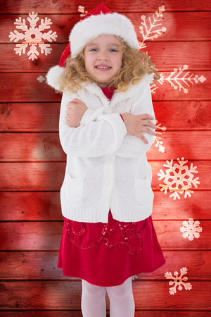 Festive little girl smiling at camera against snowflake pattern on red planksの写真素材