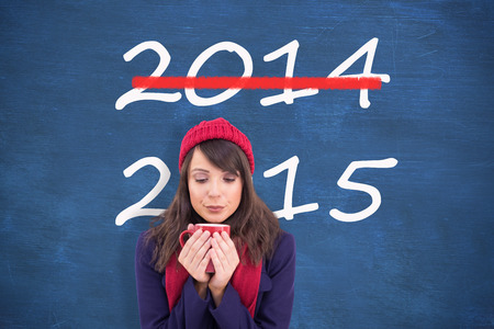 Festive brunette holding a mug against blue chalkboard