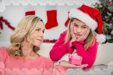 Festive mother and daughter with gift against snowflake frameの写真素材