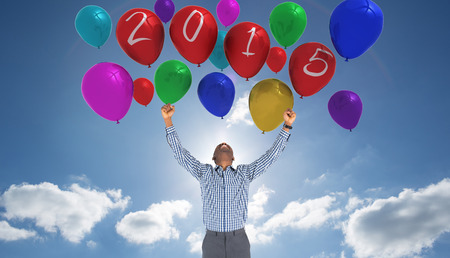 Excited businessman cheering against cloudy sky with sunshine