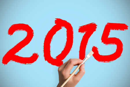 Hand holding paintbrush against blue background with vignetteの写真素材