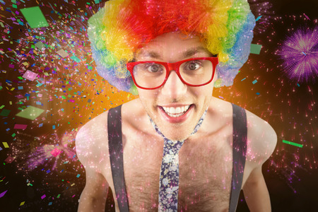 Geeky hipster in afro rainbow wig against colourful fireworks exploding on black background