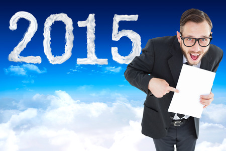 Geeky smiling businessman showing paper against bright blue sky over cloudsの写真素材