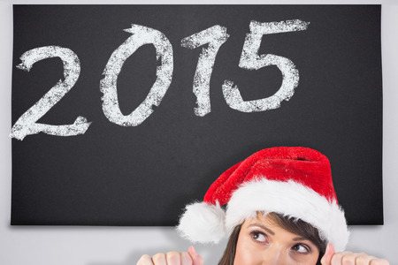 Festive brunette holding a poster while looking up against black chalkboardの写真素材