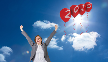 Excited redhead businesswoman cheering against bright blue sky with clouds