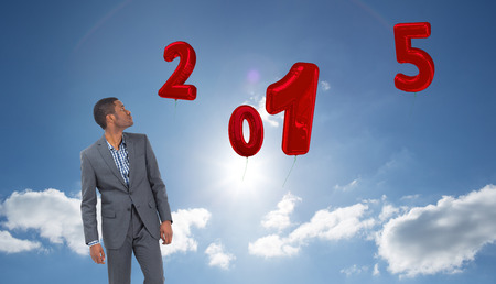 Businessman standing and looking against cloudy sky with sunshine