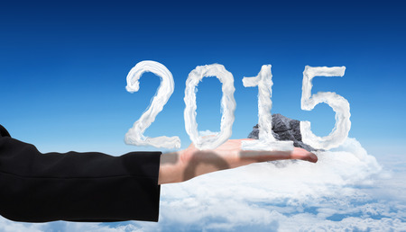 Businesswomans hand presenting against mountain peak through the cloudsの写真素材