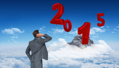 Thinking businessman against mountain peak through cloudsの写真素材