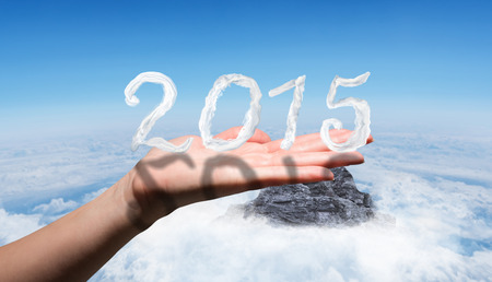 Hand showing against mountain peak through the cloudsの写真素材