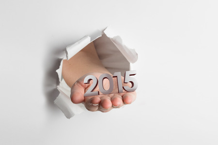 Hand presenting through paper against 2015の写真素材