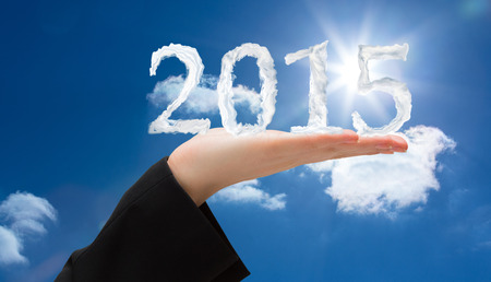 Hand presenting against bright blue sky with cloudsの写真素材