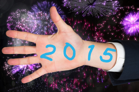 Hand with fingers spread out against colourful fireworks exploding on black backgroundの写真素材