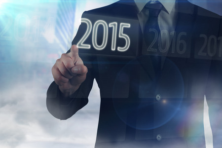 Businessman in suit pointing finger against 2015 on interface