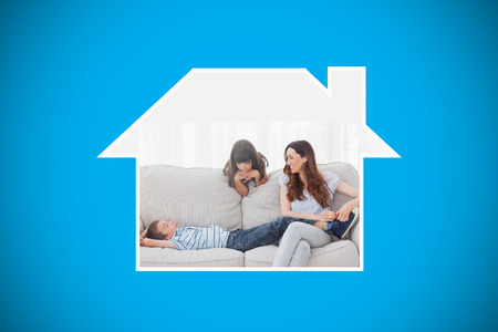 Mother sitting with her children on sofa against blue background with vignetteの写真素材