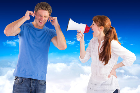 Woman shouting through a megaphone against bright blue sky over cloudsの写真素材