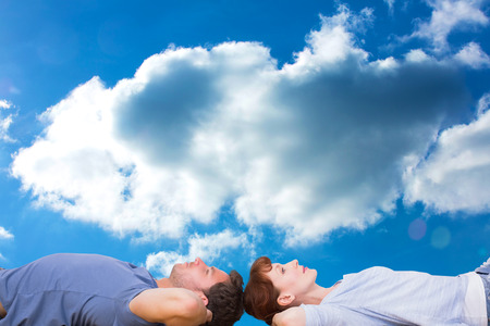 Couple lying on the floor against cloudy skyの写真素材
