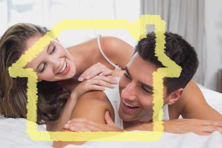 Romantic young couple in bed at home against house outlineの写真素材