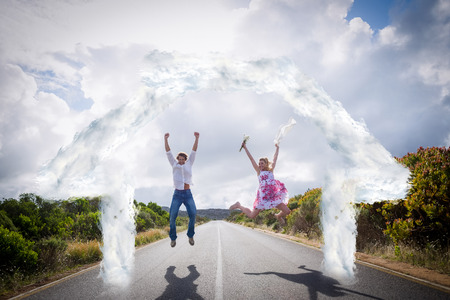 Excited couple jumping on the road against house outline in cloudsの写真素材