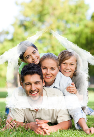 Happy family in the park against house outline in cloudsの写真素材