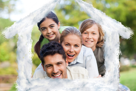 Happy family in the park against house outline in cloudsの写真素材