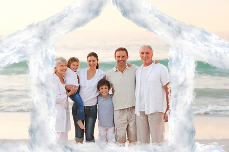 Beautiful family at the beach against house outline in cloudsの写真素材