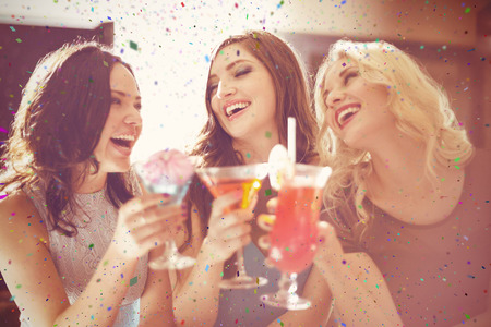 Attractive friends drinking cocktails together against flying coloursの写真素材