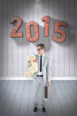 Businessman holding teddy bear  against grey roomの写真素材