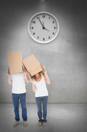 Mature couple wearing boxes over their heads against grey roomの写真素材