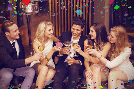 Happy friends having a drink together against flying colours